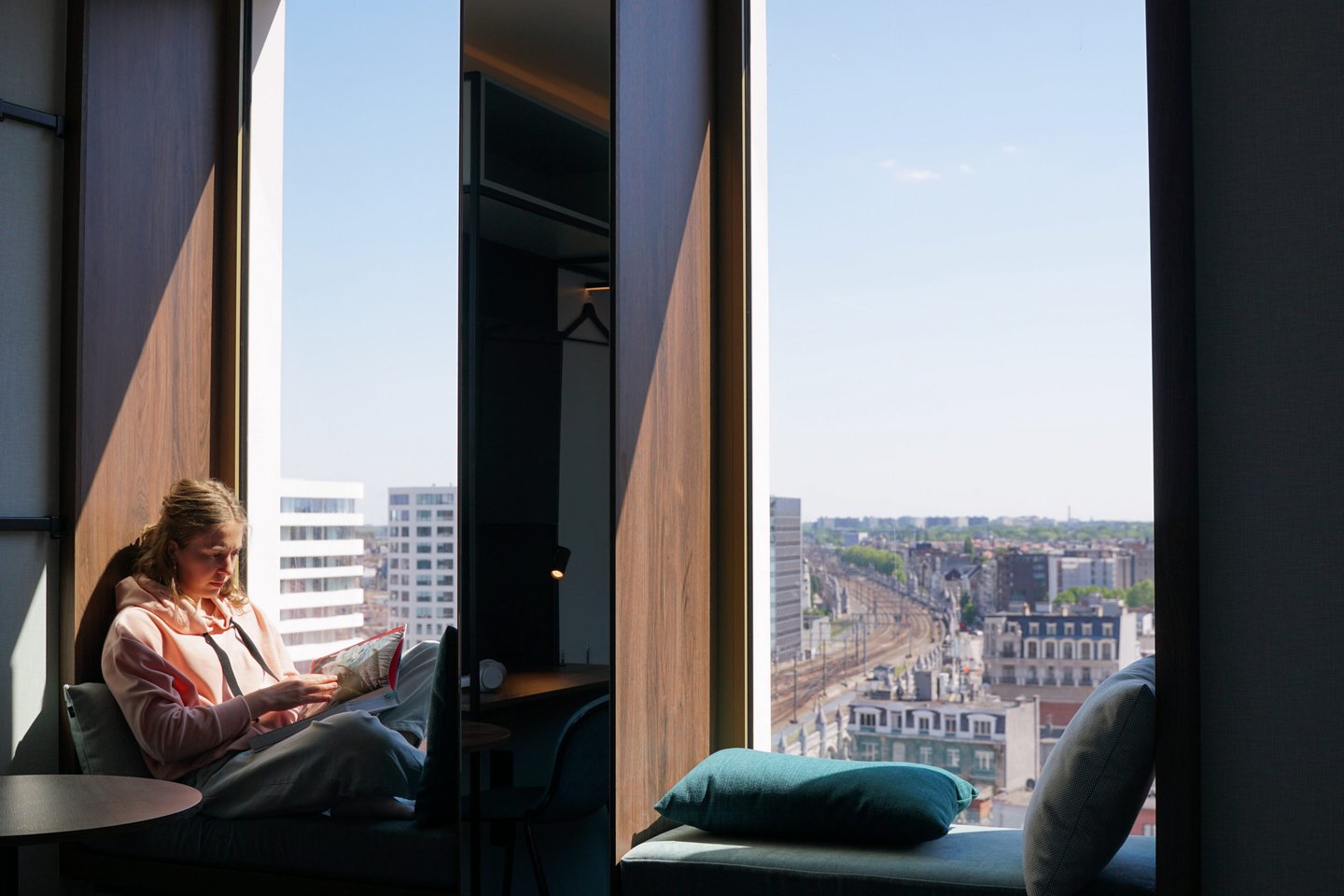 Guest reading in the window seat with a view over the Antwerp rooftops
