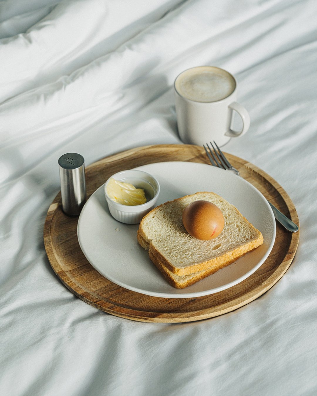 Ontbijt op een dienblad in bed: gekookt ei, toast en koffie